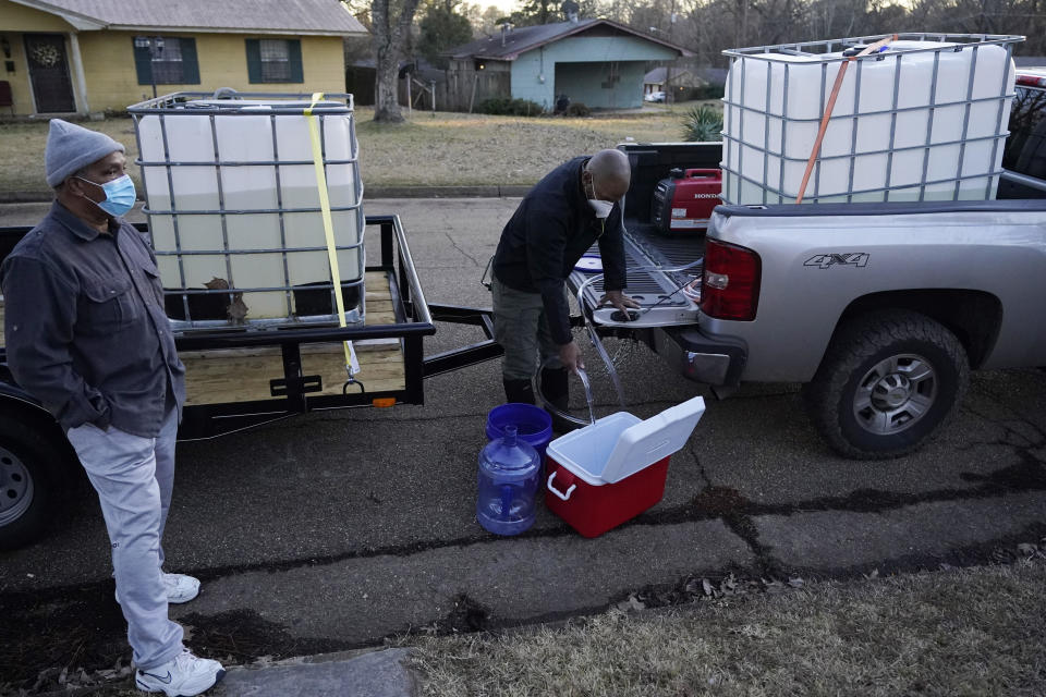 City of Jackson councilman and State Representative De'Keither Stamps pours potable water into an ice chest and empty jugs as a resident watches in Jackson, Mississippi, on Monday afternoon, February 22, 2021.  / Credit: Rogelio V. Solis / AP