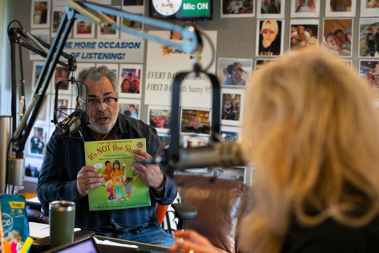 Morning show radio personality at WSNY (94.7 FM) Dino Tripodis displays a children's book called "It's NOT the stork!" to longtime co-host Stacy McKay during an Aug. 20 broadcast of "Sunny This Morning with Stacy McKay and Dino Tripodis." Tripodis was at Sunny 95 for 24 years before he left in 2018 to pursue his own creative projects. He returned in July.
