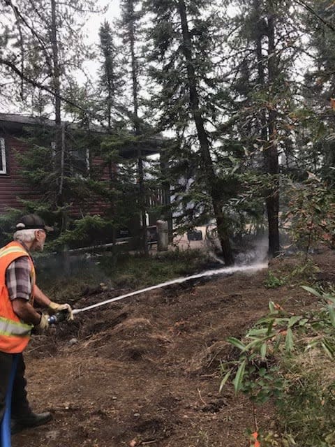 Alan Kimball hoses down the brush beside homes under threat of wildfire in Enterprise, N.W.T.