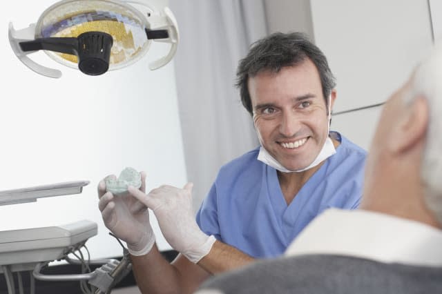 Dentist showing patient a mold of teeth and smiling