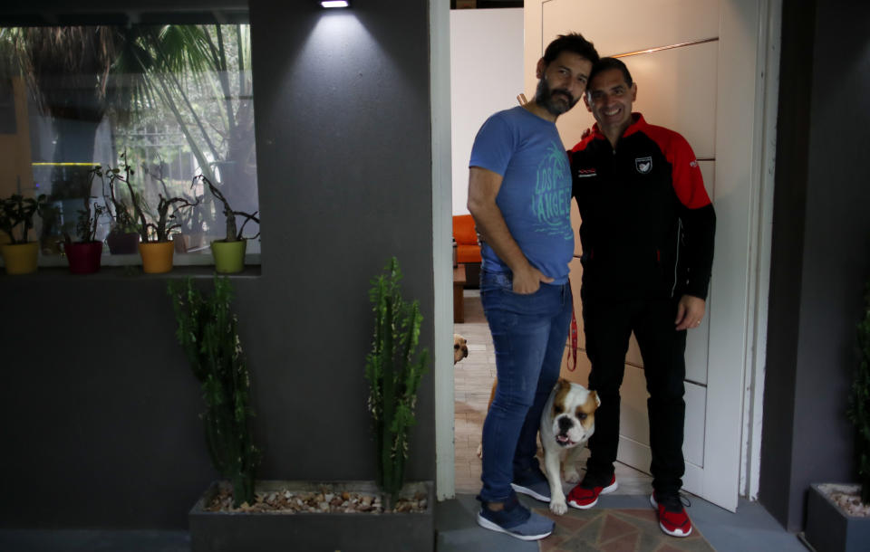 Former Catholic Priest Andres Gioeni, right, poses for a photo with his husband Luis Iarocci and their dog Boris after they got home from the bishopric where he started the process of apostasy in Buenos Aires, Argentina, Wednesday, March 17, 2021. Gioeni, who left the priesthood 20 years ago and married in 2014, said he has decided to formally leave the church after the Vatican decreed that the Catholic Church cannot bless same-sex unions since God ‘cannot bless sin.’ (AP Photo/Natacha Pisarenko)