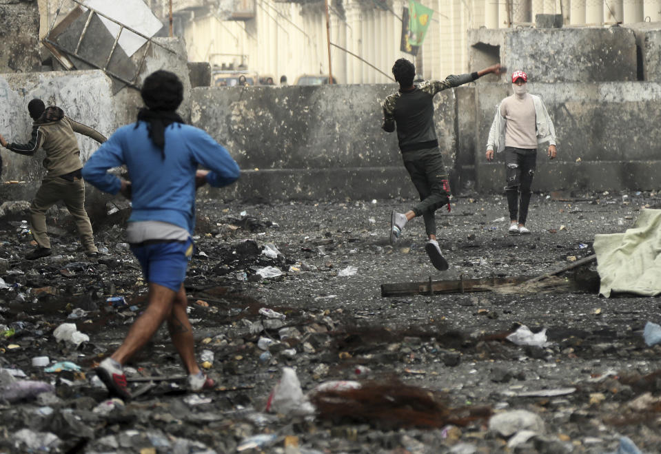 Anti-government protesters throw stones while security forces close Rasheed Street during clashes in Baghdad, Iraq, Friday, Dec. 6, 2019. (AP Photo/Hadi Mizban)