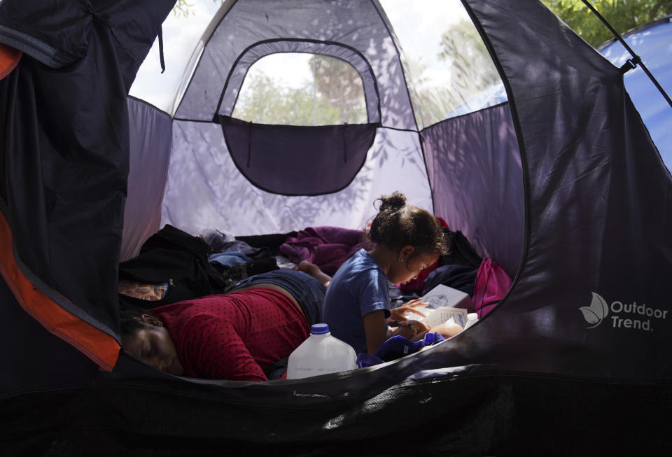 In this Aug. 30, 2019, photo, asylum seeker Yareni G. Aguilar, 5, flips through the pages of a book in an encampment where she lives near the Gateway International Bridge in Matamoros, Mexico. Most of the migrants living there have been sent back to Mexico to wait for their asylum case under the "Remain in Mexico" program, officially called the Migrant Protection Protocols. (AP Photo/Veronica G. Cardenas)