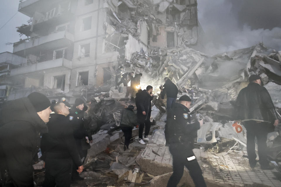 Emergency workers clear the rubble after a Russian rocket hit a multistory building leaving many people under debris in Dnipro, Ukraine, Saturday, Jan. 14, 2023. (AP Photo/Roman Chop)