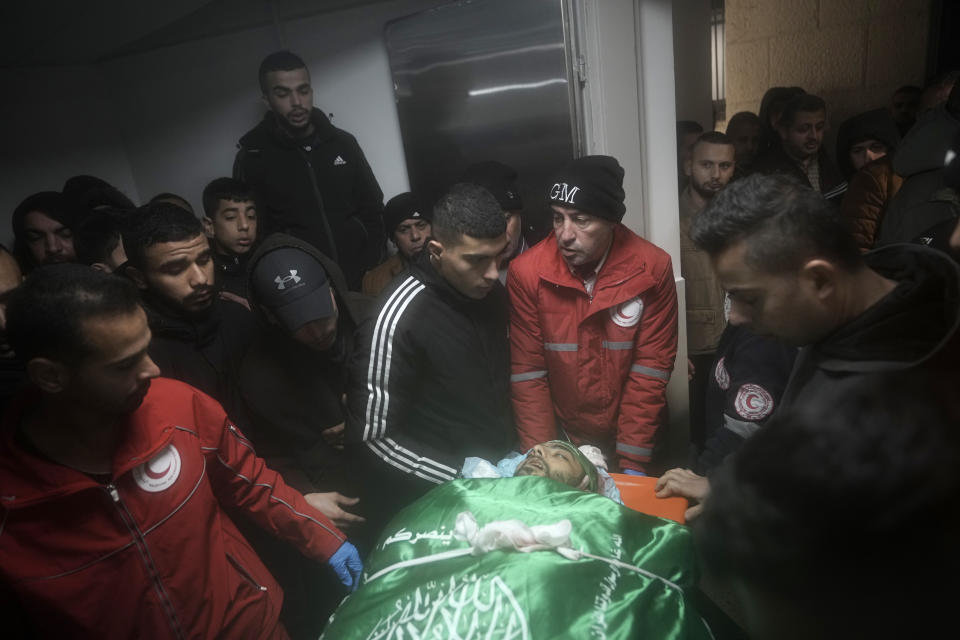 Palestinians gather around the body of Muhammad Jalamneh, draped in the Hamas militant group flag, in the morgue of Ibn Sina Hospital after he was killed in an Israeli military raid in the West Bank town of Jenin, Tuesday, Jan. 30, 2024. Armed Israeli undercover forces disguised as women and medical workers stormed the hospital on Tuesday, killing a few Palestinian militants. The Palestinian Health Ministry condemned the incursion on a hospital, where the military said the militants were hiding out.(AP Photo/Majdi Mohammed)