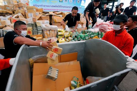 Thai narcotics officials put bags of heroin into a bin during the 47th Destruction of Confiscated Narcotics ceremony in Ayutthaya province, north of Bangkok, Thailand June 26, 2017. REUTERS/Chaiwat Subprasom