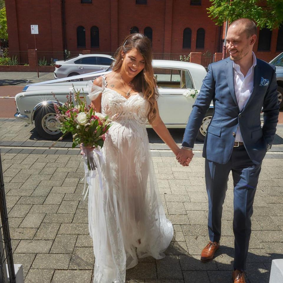 Tracey Jewel holds hands with her husband in her wedding dress