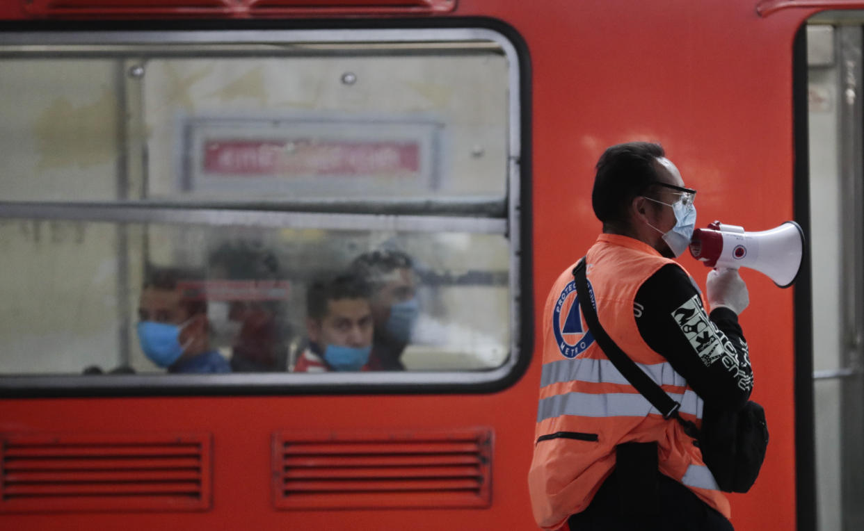 A civil protection worker subway worker wearing a mask against the spread of the new coronavirus gives instructions to commuters at the Pino Suarez subway station in Mexico City, Thursday, May 14, 2020.. (AP Photo/Eduardo Verdugo)