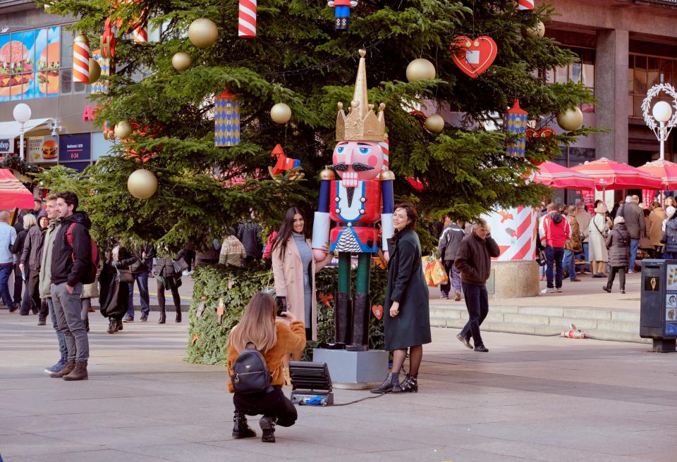 Adventes tirgus centrālajā laukumā divas sievietes stāv pie Riekstkodis statujas pie lielas Ziemassvētku eglītes.  Zagreba, Horvātija