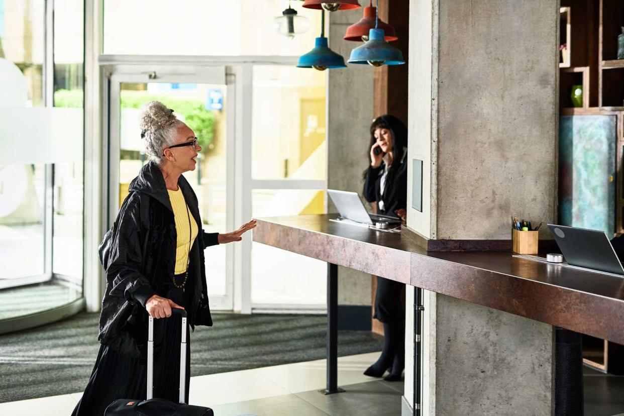 Woman in front of hotel reception desk talking and gesturing