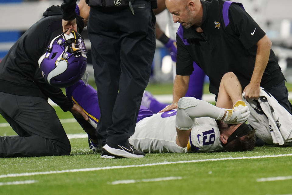 Team officials look over Minnesota Vikings wide receiver Adam Thielen during the first half of an NFL football game against the Detroit Lions, Sunday, Dec. 5, 2021, in Detroit. (AP Photo/Paul Sancya)