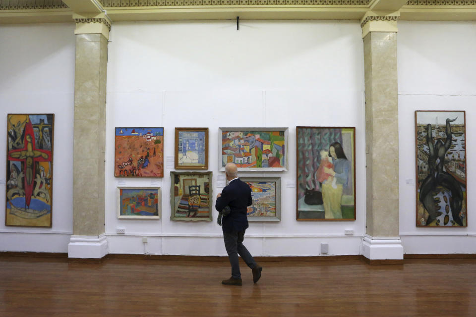 A man looks at paintings during an exhibition of culturally significant paintings that were recently exchanged as part of an effort to boost confidence between the ethnically divided island nation's two communities, at the Ledra Palace Hotel inside the UN controlled buffer zone in divided capital Nicosia, Cyprus, Monday, Feb. 3, 2020. Cyprus' President Nicos Anastasiades and the leader of the ethnically divided island's breakaway Turkish Cypriots Mustafa Akinci attended the exhibition. (AP Photo/Petros Karadjias)