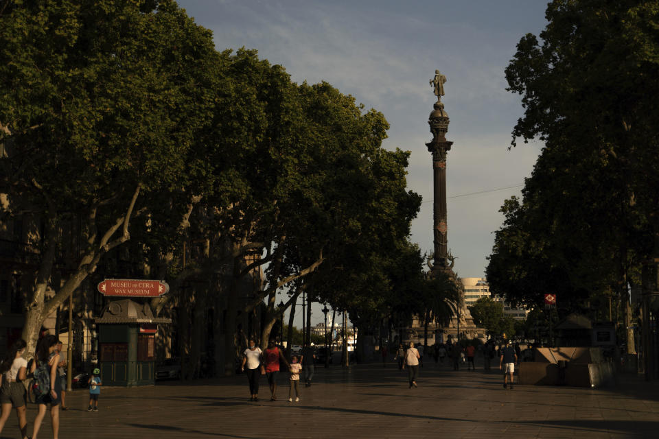 People walk on Las Ramblas as the statue of Christopher Columbus stands atop a 200-ft tall pedestal at the end of the sea-side promenade in Barcelona, Spain, Thursday, July 2, 2020. Unlike in the United States, Britain and Belgium, statues of colonial-era figures have not become a major source of protests in Spain, which once ruled over one of the largest empires in history after conquering much of the Americas. Barcelona Mayor Ada Colau is one of the few public officials who say Spain must revisit its colonial legacy - though she is against timid calls to remove the city’s monument to Christopher Columbus. Instead, she tells The Associated Press that she encourages a public discussion about the Italian explorer whose landing in the Caribbean in 1492 gave birth to Spain’s overseas empire. (AP Photo/Renata Brito)