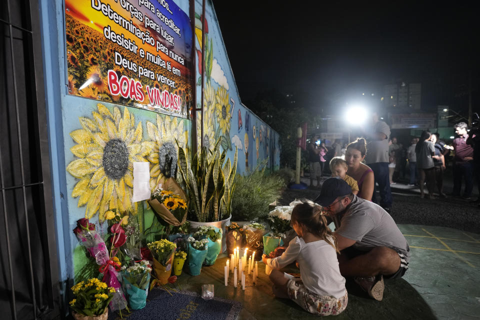 FILE - A family lights a candle at a makeshift memorial at the "Cantinho do Bom Pastor" daycare center after a fatal attack on children in Blumenau, Brazil, April 5, 2023. Brazil is grappling with a wave of violence in its schools. The government has sought input from independent researchers and convened a meeting on Tuesday, April 18, 2023, of ministers, mayors and Supreme Court justices to discuss possible solutions. (AP Photo/Andre Penner, File)