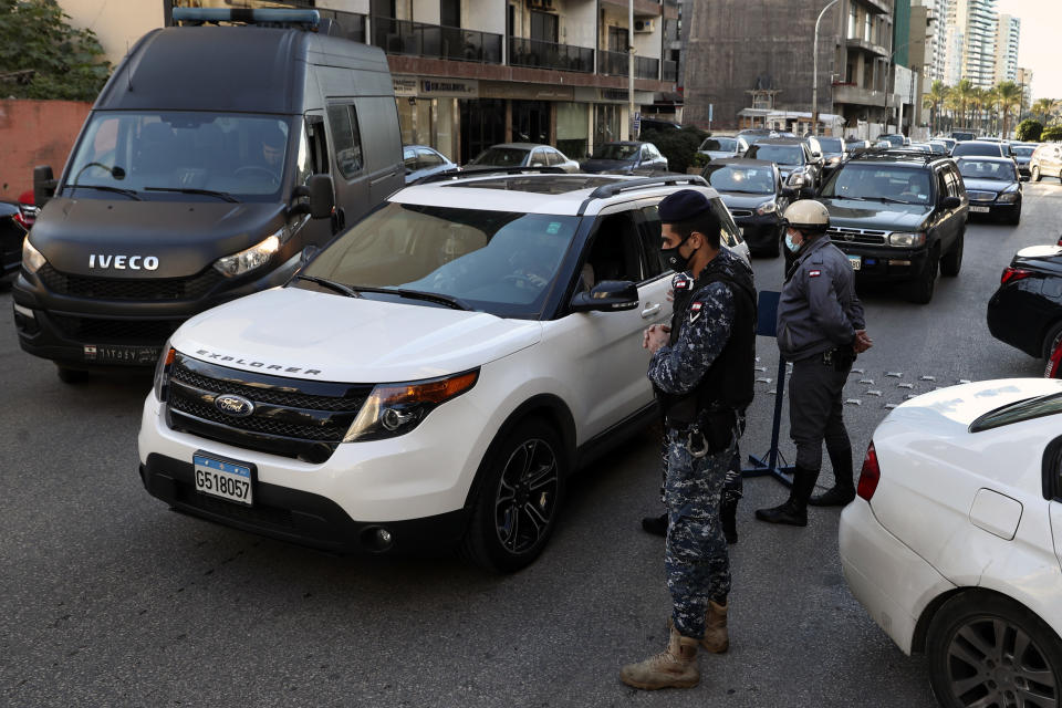 Police officers at a checkpoint look for violations of a lockdown to help prevent the spread of the coronavirus, in Beirut Lebanon, Thursday, Jan. 21, 2021. Authorities on Thursday extended a nationwide lockdown by a week to Feb. 8 amid a steep rise in coronavirus deaths and infections that has overwhelmed the health care system. (AP Photo/Bilal Hussein)