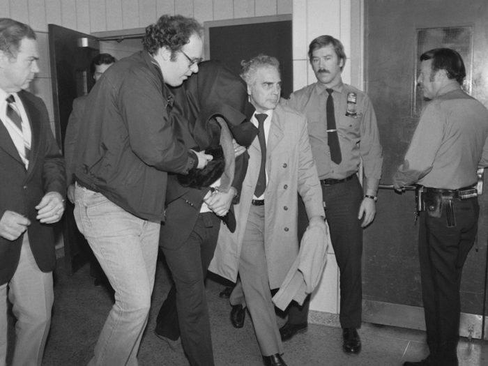 Mark David Chapman is escorted out of police station early on December 9th.