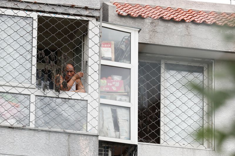 A man looks on from a window at a residential compound that is under lockdown in the Fengtai district, in Beijing