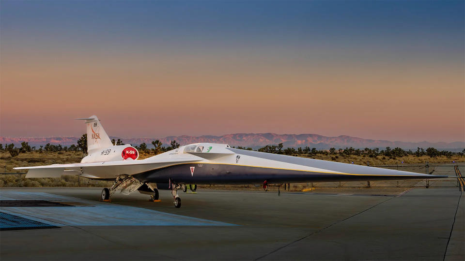 a long blue-and-white jet with a colorful sunrise behind it