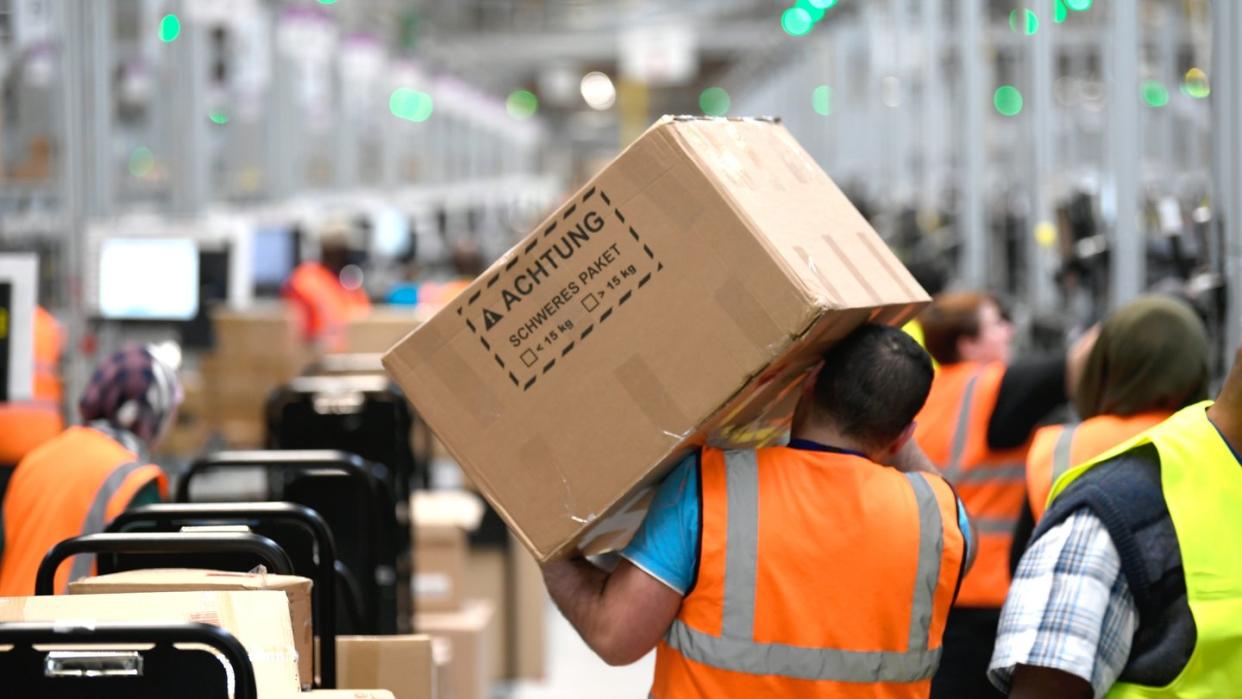 Ein Mitarbeiter trägt ein Paket im Logistikzentrum des Versandhändlers Amazon.