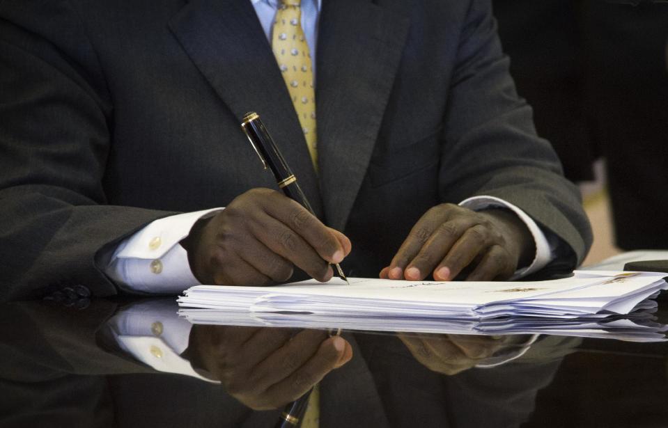 Uganda's President Yoweri Museveni signs a new anti-gay bill that sets harsh penalties for homosexual sex, in Entebbe, Uganda Monday, Feb. 24, 2014. Museveni on Monday signed the controversial anti-gay bill into law, with penalties including 14 years in jail for first-time offenders and life imprisonment as the maximum penalty for "aggravated homosexuality", saying it is needed to deter what he called the West's "social imperialism" promoting homosexuality in Africa. (AP Photo/Rebecca Vassie)