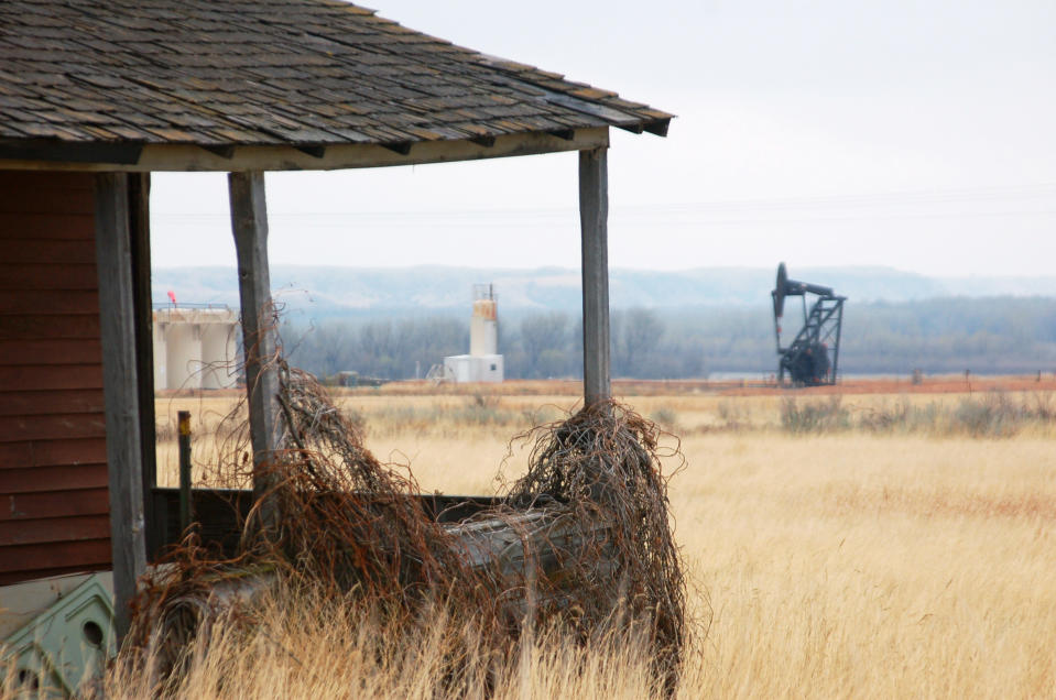 In this April 19, 2012, photo a nodding donkey pump extracts oil from the earth at an abandoned farm near the old ghost town of Dore, N.D. Dore has seen a rebirth with the booming oil activity in western North Dakota. (AP Photo/ James MacPherson)