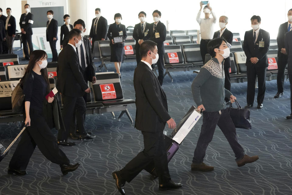 Japan's former Princess Mako, left, the elder daughter of Crown Prince Akishino, and her husband Kei Komuro, right, walk to board an airplane to New York Sunday, Nov. 14, 2021, at Tokyo International Airport in Tokyo. (AP Photo/Eugene Hoshiko)