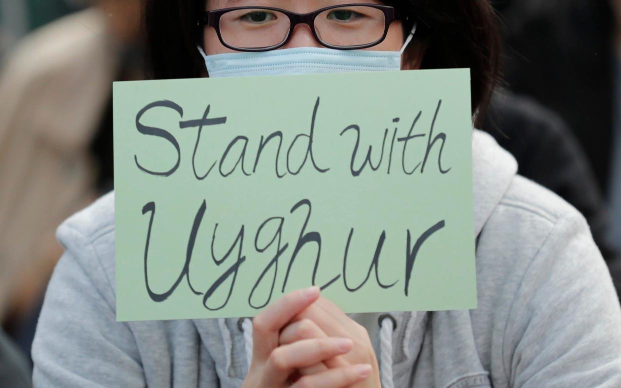 A man holds a sign during a rally to show support for Uighurs and their fight for human rights in Hong Kong - Lee Jin-man/AP