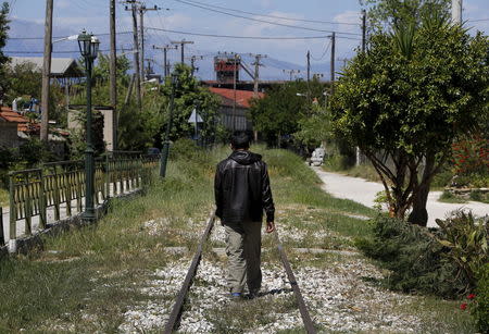 An Afghan immigrant walks on unused rail tracks by the ferry terminal in the western Greek town of Patras May 4, 2015. REUTERS/Yannis Behrakis