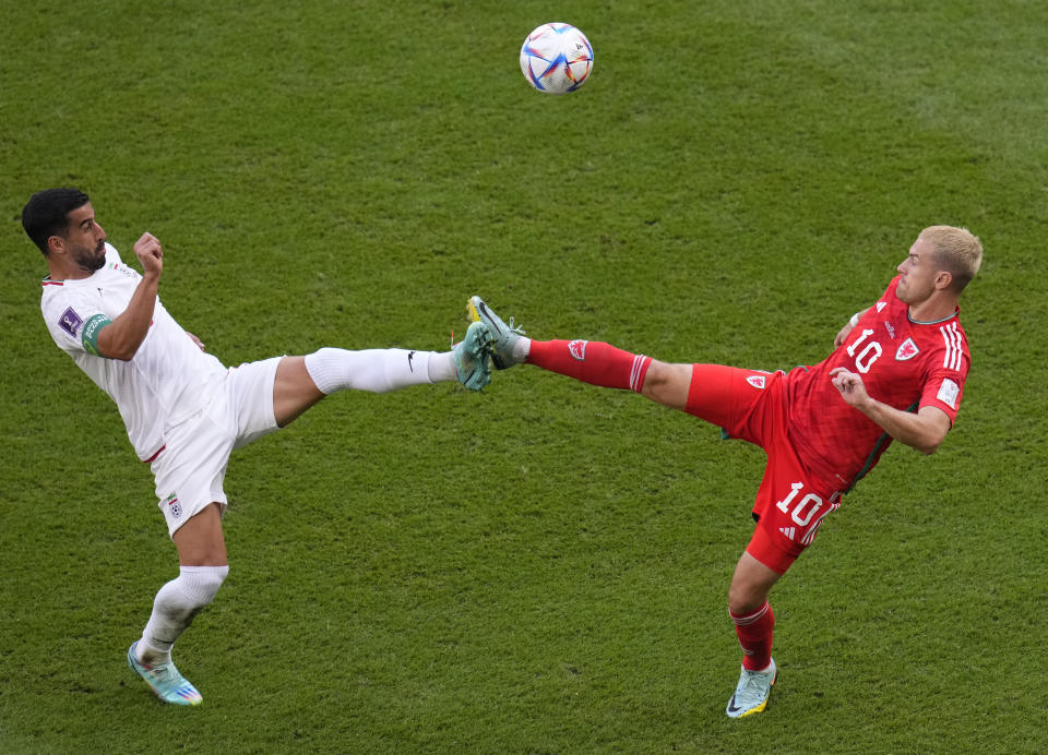 Iran's Ehsan Hajsafi, left, duels for the ball with Wales' Aaron Ramsey during the World Cup group B soccer match between Wales and Iran, at the Ahmad Bin Ali Stadium in Al Rayyan , Qatar, Friday, Nov. 25, 2022. (AP Photo/Manu Fernandez)