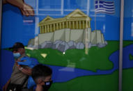 People wearing face masks to protect against the spread of the new coronavirus, walk in front of a toy store in Athens, Tuesday, Aug. 11, 2020. Greece's government announced additional restrictions Monday aimed at curbing a flare-up of coronavirus cases that has led to a spike of new daily infections and an increase in the number of critically ill people in the country. (AP Photo/Thanassis Stavrakis)