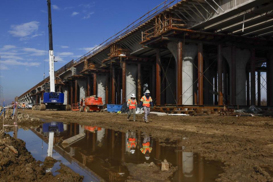 Two people stand under a construction site.