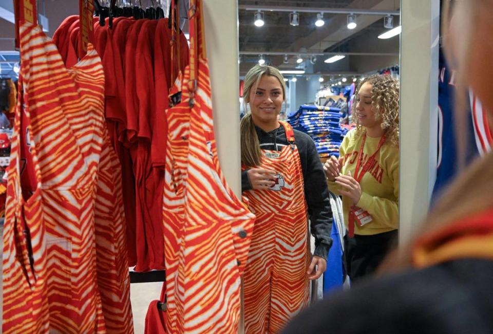 Sales associate Payton Rayos, left, had help from Jade Williams, a manager in training, when she tried on the Chiefs red lined zebra pants on Tuesday at Rally House Legends in Kansas City, Kansas. The $120 pants are a hot-selling item at the store.