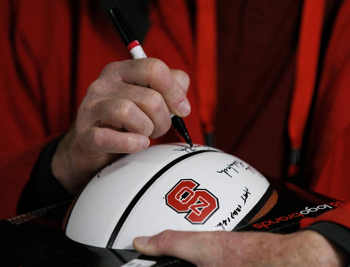 Steve Smith autographs a basketball following a halftime ceremony to honor members of the N.C. State men’s basketball 1974 national championship team on Saturday, Feb. 24, 2024, at PNC Arena in Raleigh, N.C.