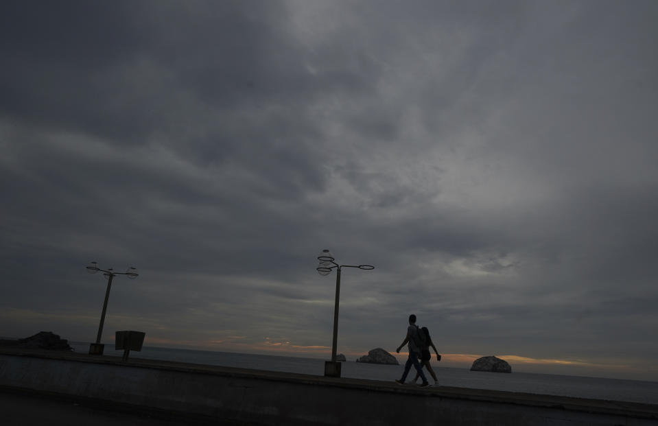 A couple walks at the beachfront in Mazatlan, Mexico, Sunday, Oct. 2, 2022. Hurricane Orlene, at Category 3 strength, is heading for a collision with Mexico's northwest Pacific coast between the tourist towns of Mazatlan and San Blas. (AP Photo/Fernando Llano)
