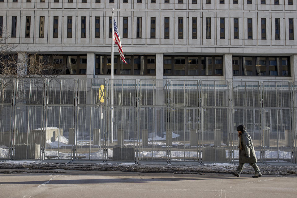A pedestrian makes his way in front of a gated Warren E. Burger Federal Building as jury selection begins in St. Paul, Minn., Thursday, Jan. 20, 2021. Jury selection began Thursday in the federal trial of three Minneapolis police officers charged in George Floyd’s killing, with the judge stressing repeatedly that fellow Officer Derek Chauvin's conviction on state murder charges and guilty plea to a federal civil rights violation should not influence the proceedings. (Elizabeth Flores/Star Tribune via AP)