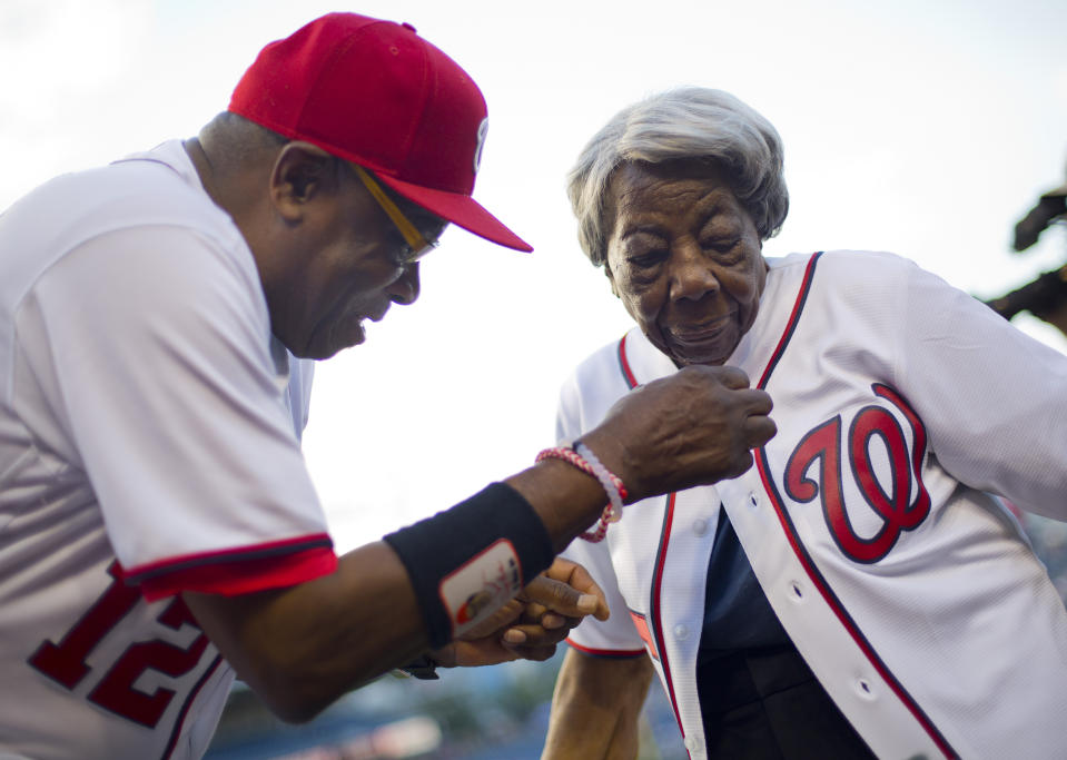 FILE - Washington Nationals manager Dusty Baker helps Virginia McLaurin, 107, with her jersey on the field before the Nationals’ baseball game against the St. Louis Cardinals at Nationals Park, on May 26, 2016, in Washington. McLaurin gained Internet fame for her impromptu dance with President Barack Obama and first lady Michelle Obama during a White House reception. McLaurin's family announced her death Monday, Nov. 14, 2022. (AP Photo/Pablo Martinez Monsivais, File)