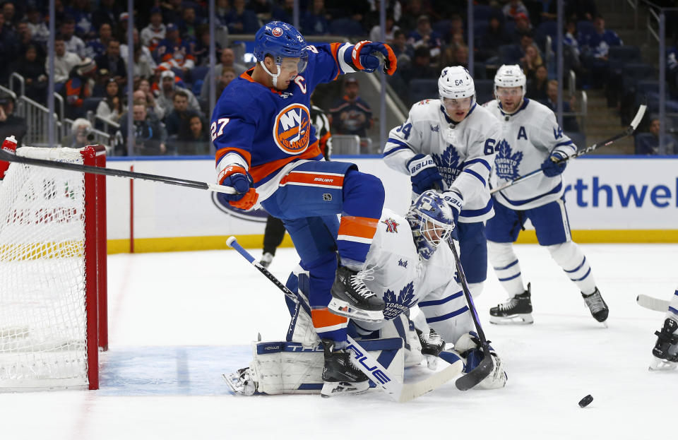 New York Islanders forward Anders Lee (27) falls over Toronto Maple Leafs goalie Ilya Samsonov as Maple Leafs center David Kampf (64) looks to clear the puck during the second period of an NHL hockey game Monday, Dec. 11, 2023, in New York. (AP Photo/John Munson)