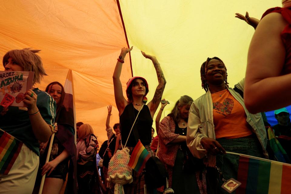 Attendees walk under a giant flag during the Marche des Fiertes LGBTQI+ (Paris annual Pride parade) in Paris, on the eve of the first round of the early French parliamentary elections in France, Saturday.