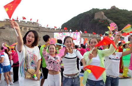 People wave Chinese national flags as they cheer after the IOC announced Beijing as the winner city for the 2022 winter Olympics bid, at the foot of the Great Wall, in Zhangjiakou, jointly bidding to host the 2022 Winter Olympic Games with capital Beijing, China, July 31, 2015. REUTERS/China Daily