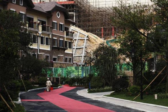 A cleaner walks in front of a house for sale at the replica village of Austria's UNESCO heritage site, Hallstatt, in China's southern city of Huizhou in Guangdong province, June 1, 2012.