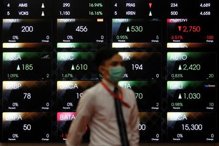 An employee walks in front of an electronic board at the Indonesia Stock Exchange (IDX) in Jakarta, Indonesia August 22, 2016. REUTERS/Iqro Rinaldi