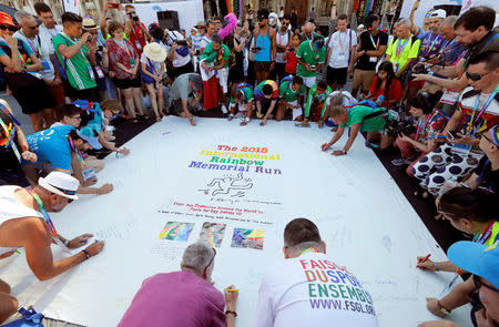 People sign a flag as they participate at the international Rainbow Memorial Run during the inauguration of the Gay Games village at the Hotel de Ville city hall in Paris, France, August 4, 2018. REUTERS/Regis Duvignau