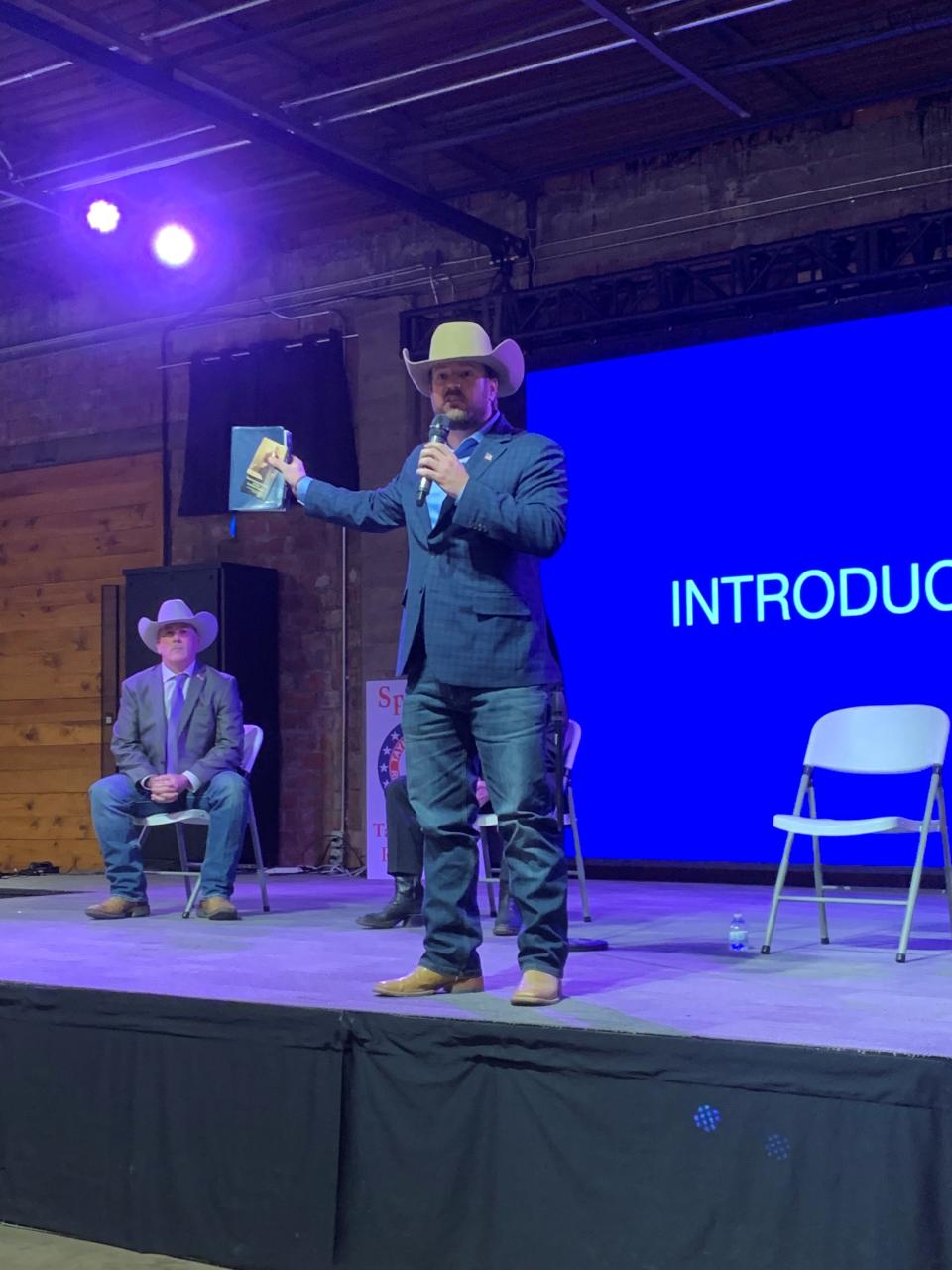 Ryan Zink, candidate for US Congress, Texas District 19, holds up a Bible and the Constitution during his intro speech at the Taylor County Republican Candidate Forum.