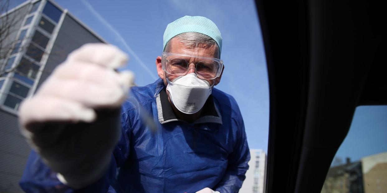 German doctor Michael Grosse takes a sample from a car driver through the window on March 27, 2020 at a drive through testing point for the novel coronavirus on a parking in Halle, eastern Germany. - German researchers plan to regularly test over 100,000 people to see if they have overcome infection with COVID-19 to track its spread, an institute behind the plan confirmed on March 27, 2020. (Photo by Ronny Hartmann / AFP) (Photo by RONNY HARTMANN/AFP via Getty Images)