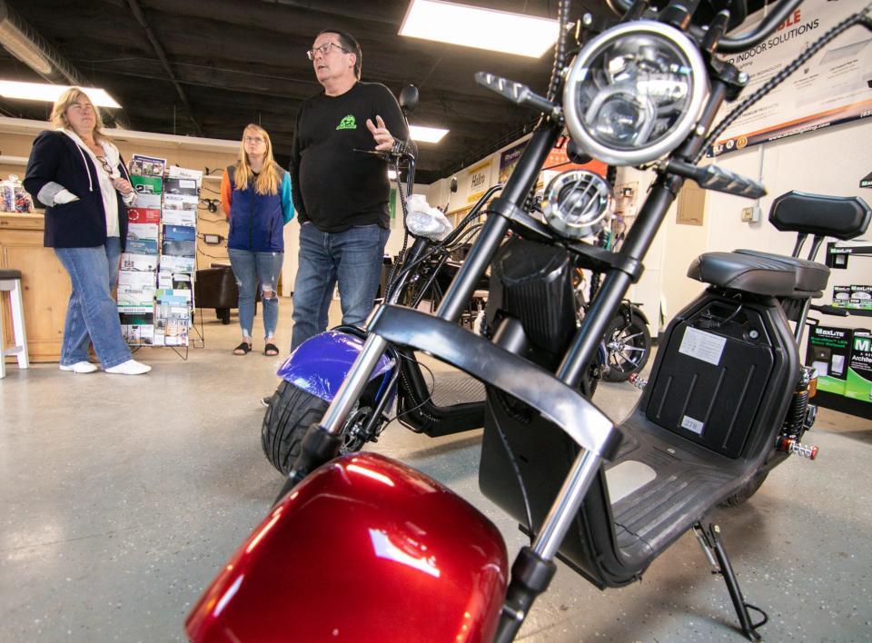 Todd Kananen, center, talks about how the family got involved in selling electric scooters with wife Nancy at far left and daughter-in-law Chandra Kananen at their MI EV Scooters store in Fowlerville Wednesday, May 25, 2022.