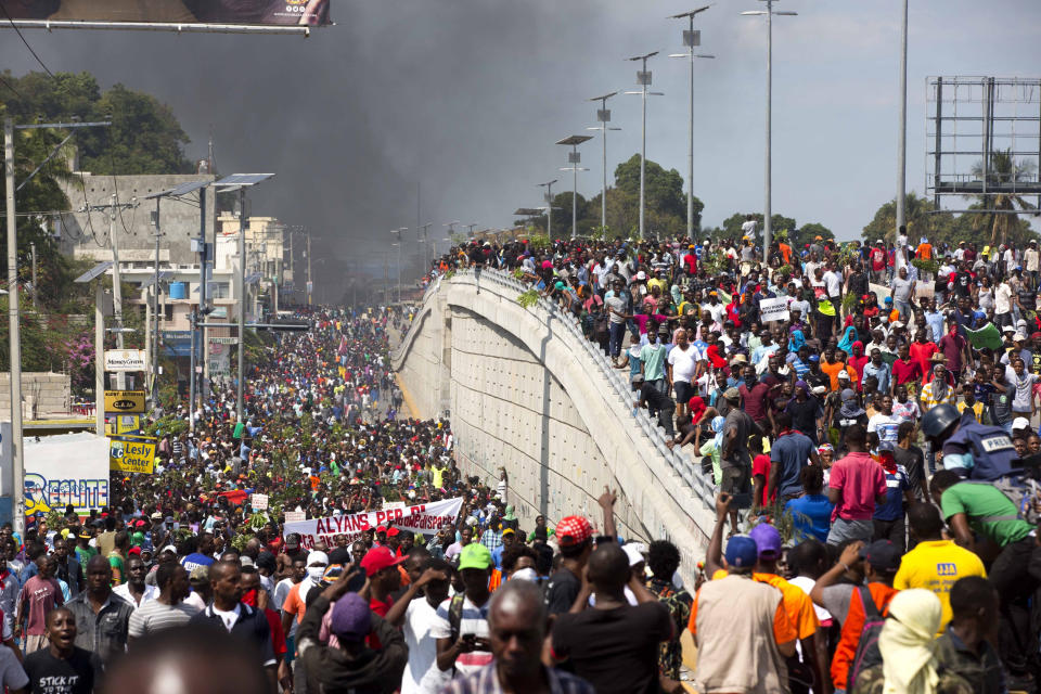 In this Feb. 7, 2019 photo, thousands of demonstrators march in the street as they chant anti-government slogans during a protest to demand the resignation of President Jovenel Moise and demanding to know how Petro Caribe funds have been used by the current and past administrations, in Port-au-Prince, Haiti. Much of the financial support to help Haiti rebuild after the 2010 earthquake comes from Venezuela's Petro Caribe fund, a 2005 pact that gives suppliers below-market financing for oil and is under the control of the central government. (AP Photo/Dieu Nalio Chery)