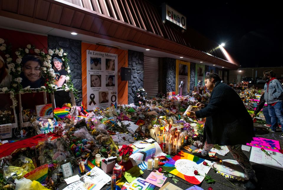 Kebrina Chirdon lights candles at a memorial outside of Club Q on Friday, Nov. 25, 2022, in Colorado Springs, Colorado. The memorial, which was moved from a sidewalk outside of police tape around the club, is made up of hundreds of bouquets of flowers, candles and notes and has been growing since early Sunday morning.