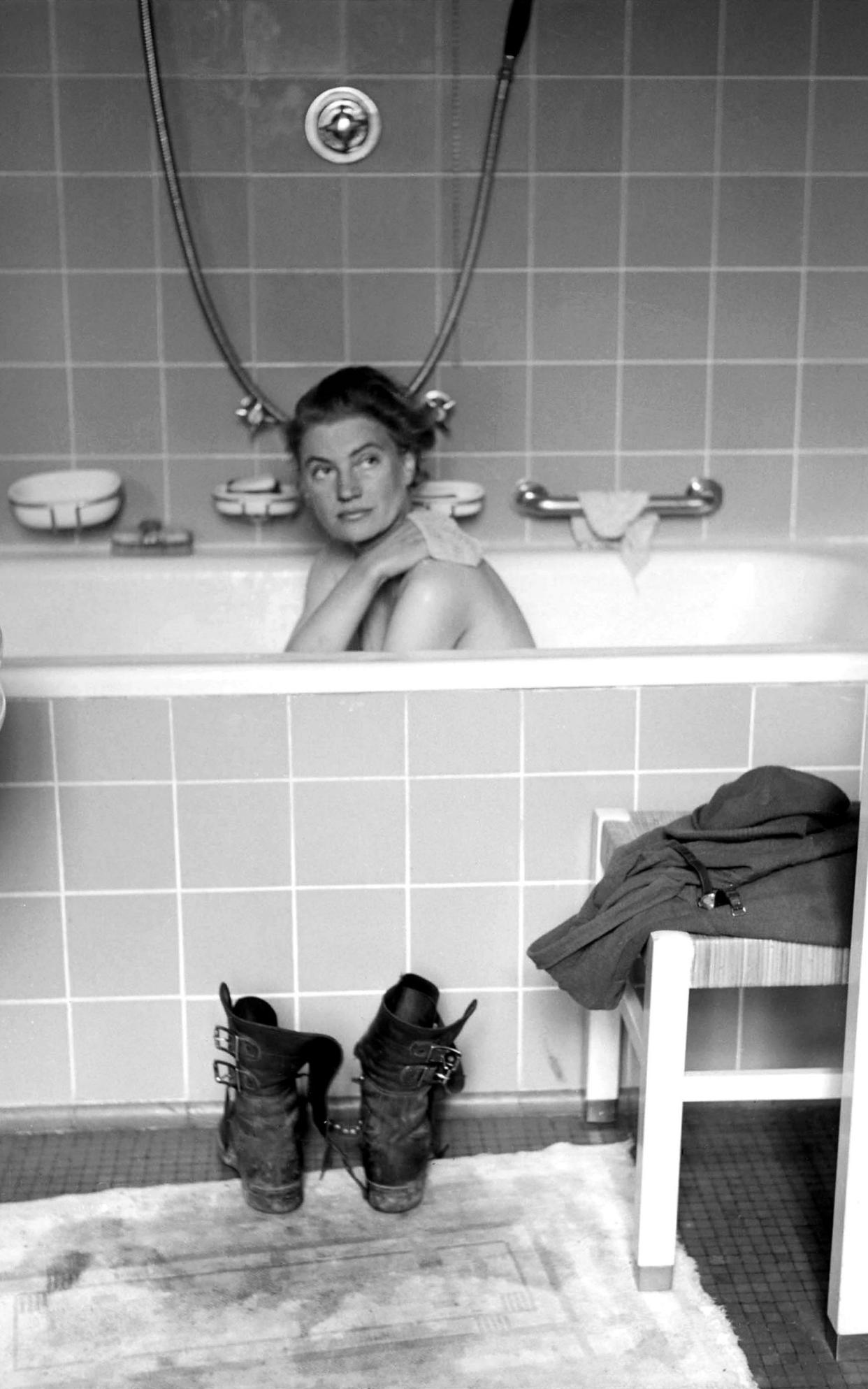 A portrait of Hitler sits on the edge of the bath, Miller's combat boots are on the floor in front of it, and her clothes and watch are on a chair
