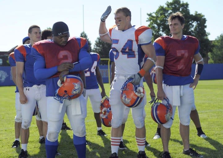 One football player reaches his hand up for a high five from a teammate.