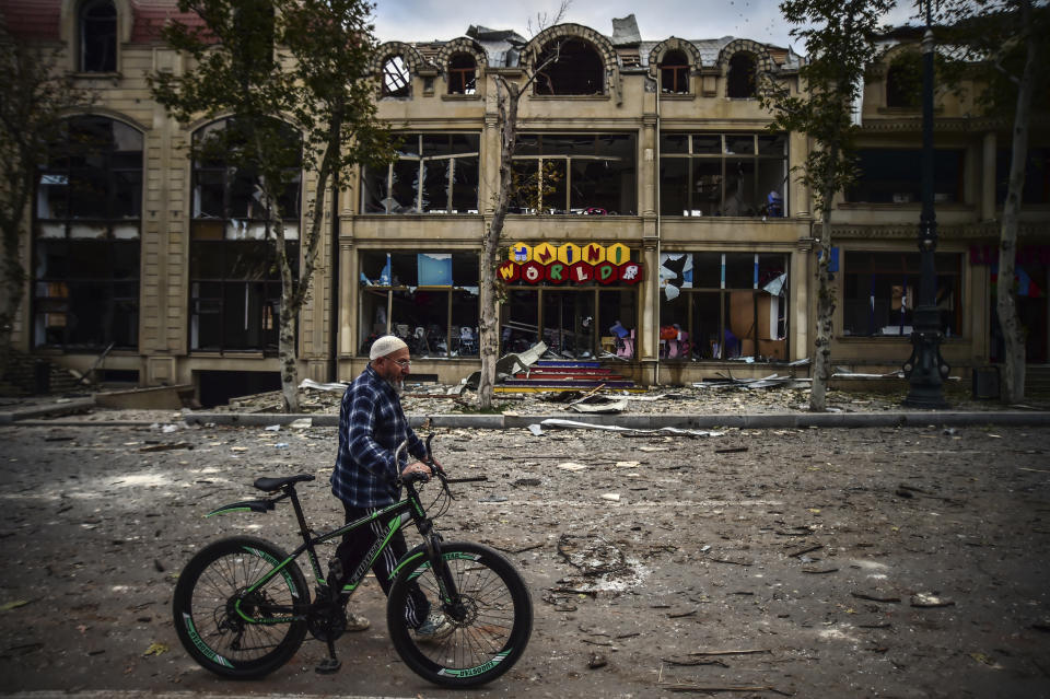 A man walks past a damaged building in a residential area in Ganja, Azerbaijan's second largest city, near the border with Armenia, after rocket fire overnight by Armenian forces, early Sunday, Oct. 11, 2020. Several civilians were killed and dozens were wounded. Russian President Vladimir Putin brokered a cease-fire on Friday in a series of calls with President Ilham Aliyev of Azerbaijan and Armenia's Prime Minister Nikol Pashinian.(Ismail Coskun/IHA via AP)